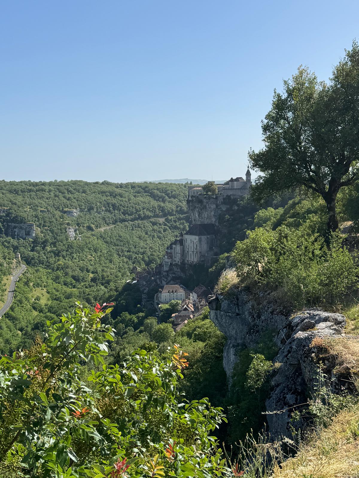 The village and sanctuary of Rocamadour clinging to a limestone cliff above a wooded gorge.